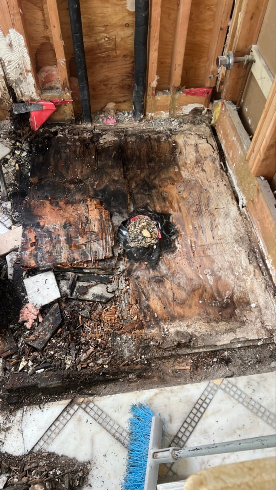 Rotted, mold-stained subfloor exposed under the master bathroom shower of a Darien, CT home before remediation, before