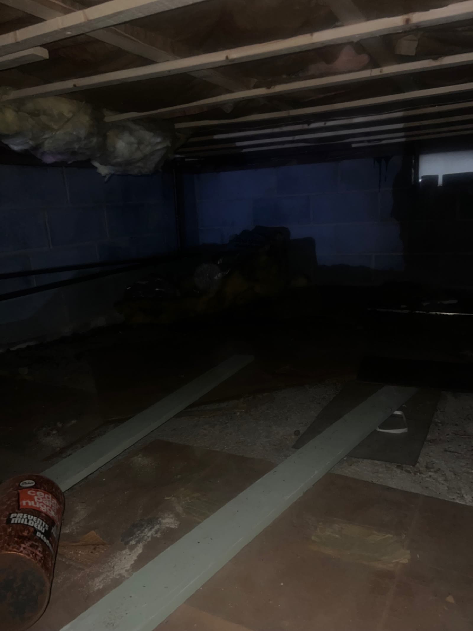 Crawl space under a Larchmont, NY home with fallen insulation and debris across the floor before cleaning
