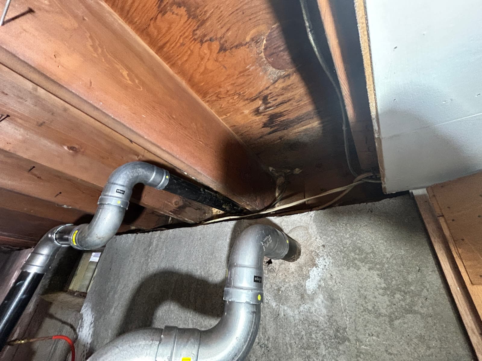 Dark water staining across floor joists above a foundation wall in a Manchester, CT home