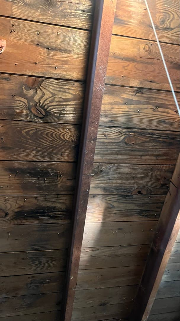 Dark staining across the underside of the plank roof boards in the attic of a pre war West Hartford, CT home before cleaning, before