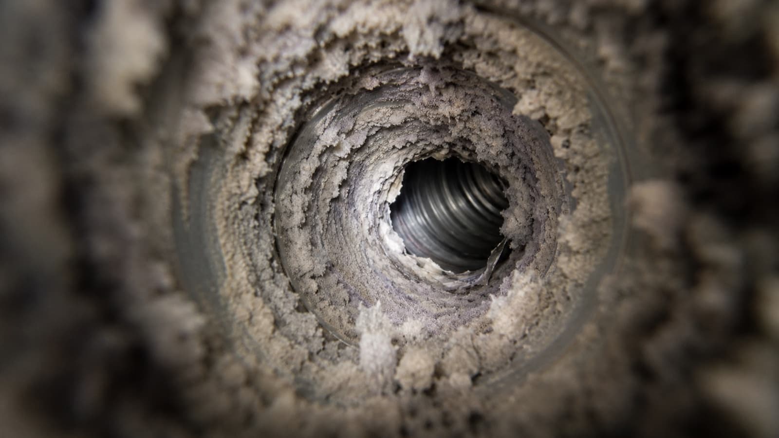 Interior of a residential dryer exhaust duct packed with compacted lint, the airflow blockage and fire risk Green Restoration removes with rotary-brush cleaning in the tri-state