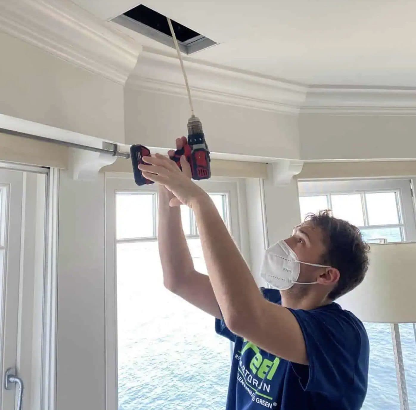Green Restoration technician cleaning a ceiling supply vent during an allergen and indoor air quality service