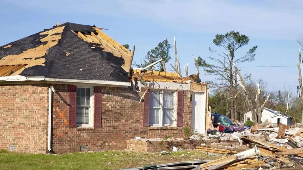 Brick home with its roof torn off and debris scattered across the yard after a severe storm, a large-loss disaster scene documented by Green Restoration large-loss PM across the tri-state
