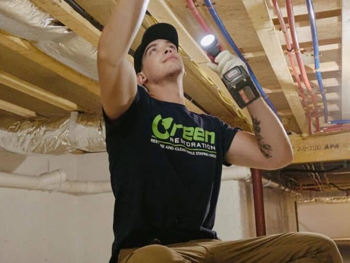 Green Restoration technician inspecting a Ansonia CT crawl space ceiling joist with a flashlight