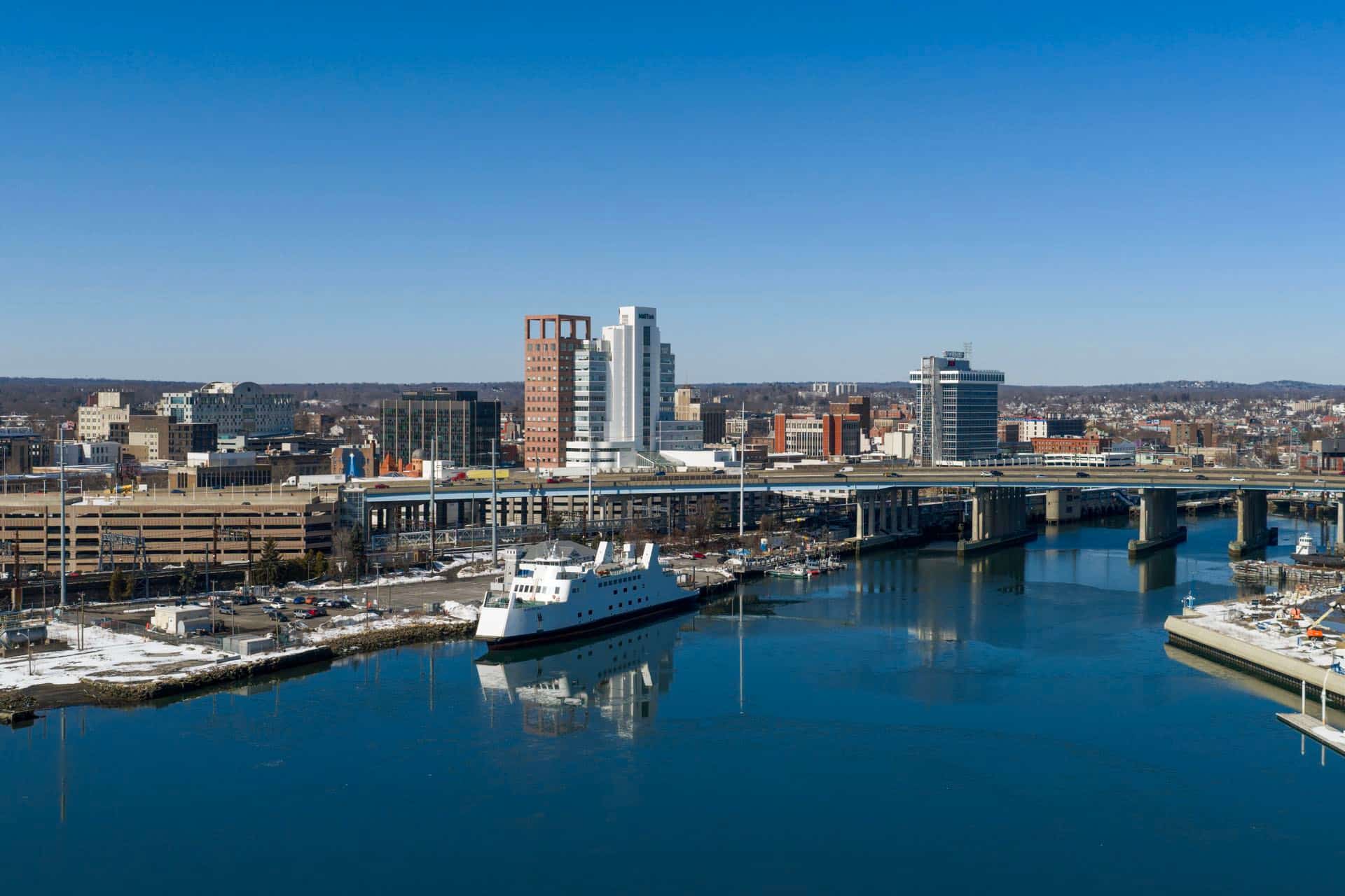Downtown Bridgeport, Connecticut skyline across the harbor with the Port Jefferson ferry. Green Restoration provides 24/7 water, fire, mold, and storm damage restoration in Bridgeport, CT.