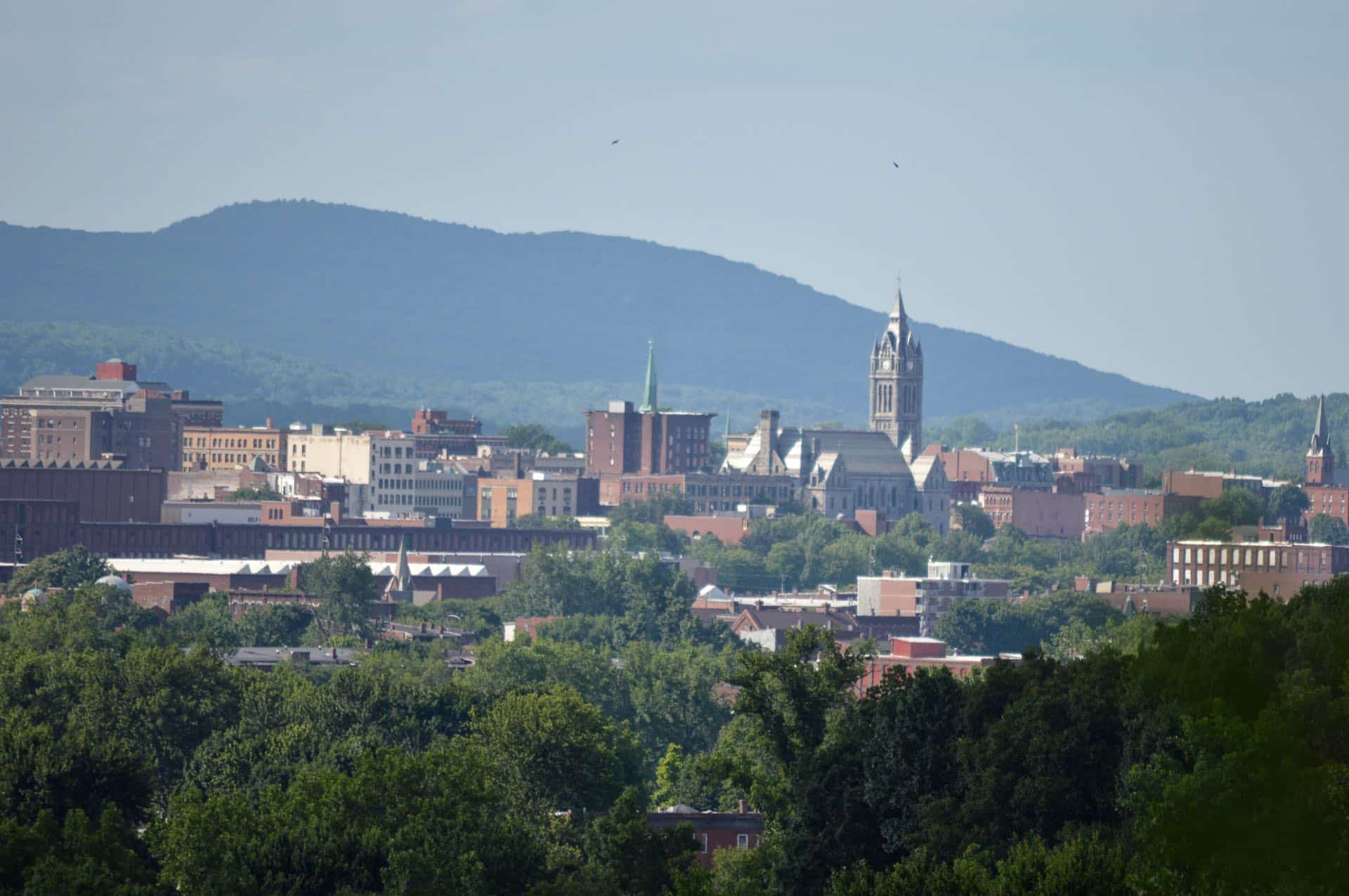 Downtown Holyoke, Massachusetts skyline with the City Hall tower and Mount Tom behind. Green Restoration provides 24/7 water, fire, mold, and storm damage restoration in Holyoke, MA.