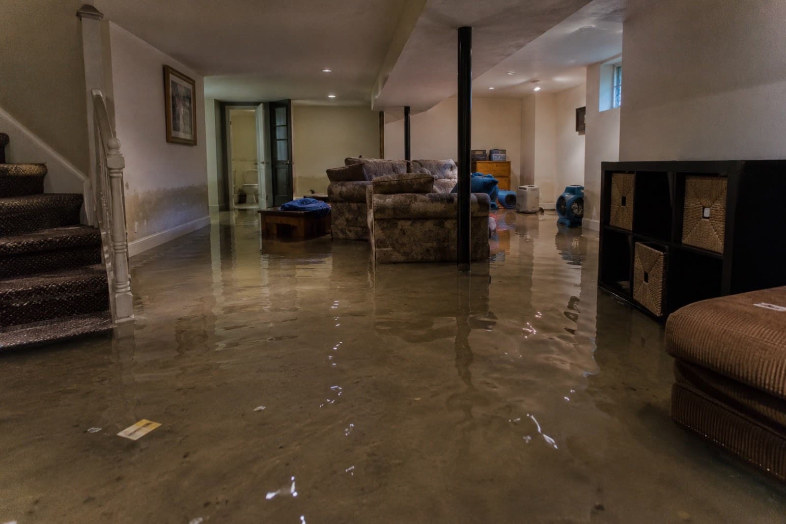 Finished basement with several inches of standing water during emergency water extraction, documented by Green Restoration